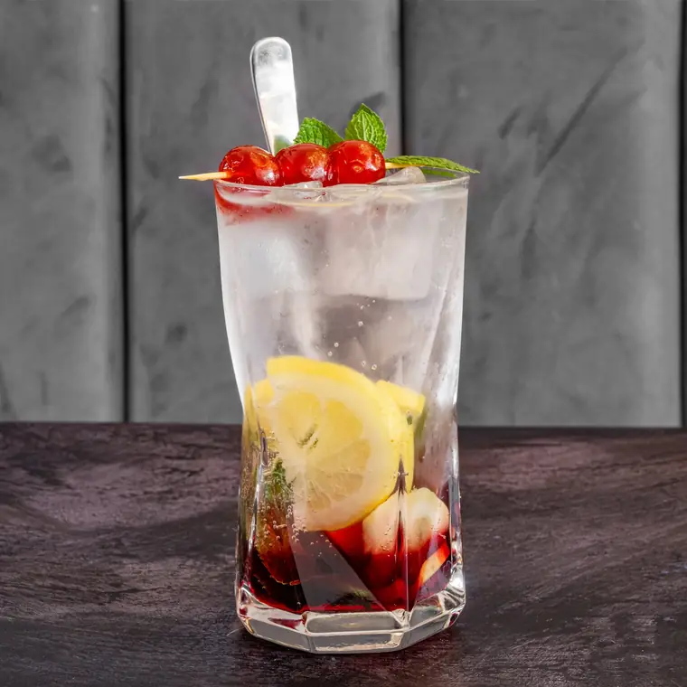 Cherry iced lemonade over ice with lemon slices and fresh mint.