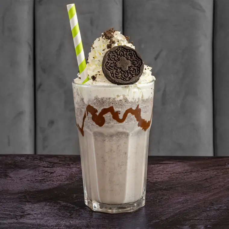 Cookies and cream milkshake topped with whipped cream and a biscuit.