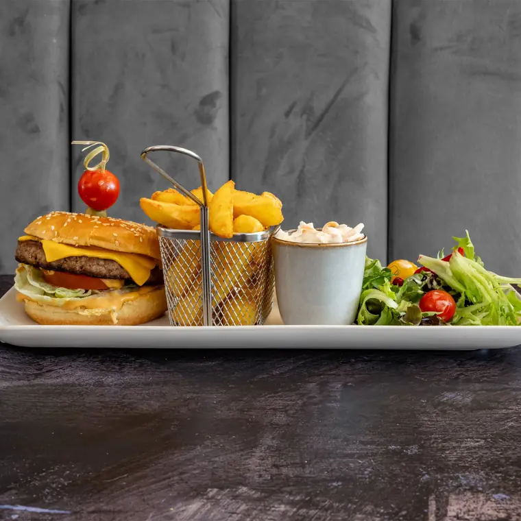 Homemade beef burger in a brioche bun with a basket of fries and side salad.